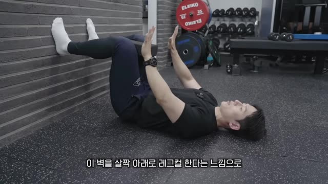 벽에 발 대고 누워서 갈비뼈 닫는 호흡(횡격막 이완) 장면